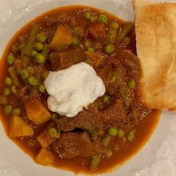 Indian curry goose meat in a bowl with naan bread