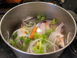 water covering fish and vegetables in stock pot