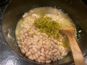 beans and chilies added to meat in pot
