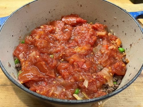 layer of tomatoes on top of meat mixture in Dutch oven